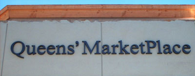 Queens Marketplace - Bronze letters on masonry wall.